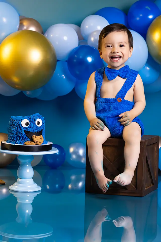 Niño celebrando su primer año en sesión de Smash Cake con globos azules